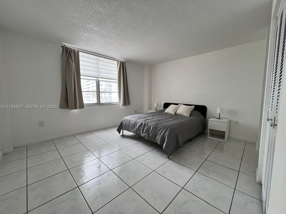 Large-format neutral tile flooring, multi-pane window, and louvered closet doors