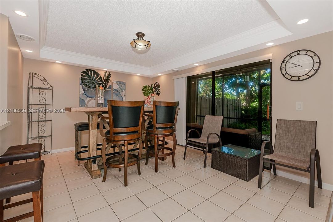 Ceramic tile flooring, crown molding, recessed lighting, and sliding glass doors