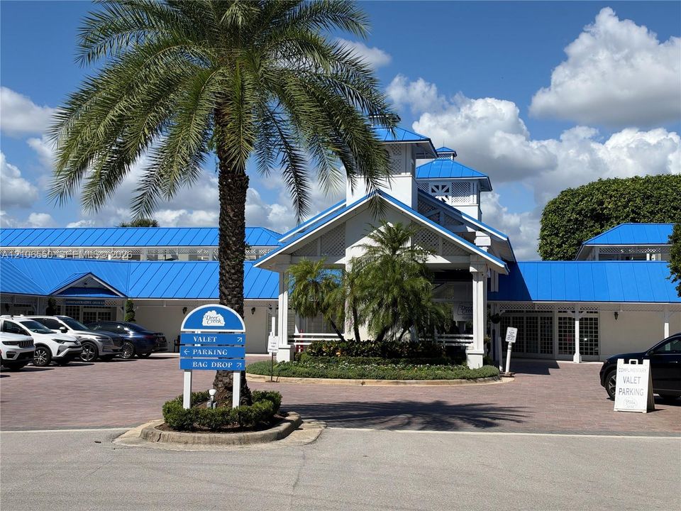 Exterior facade featuring a blue metal roof, white siding with lattice details, a covered entry portico, and a paver stone motor court