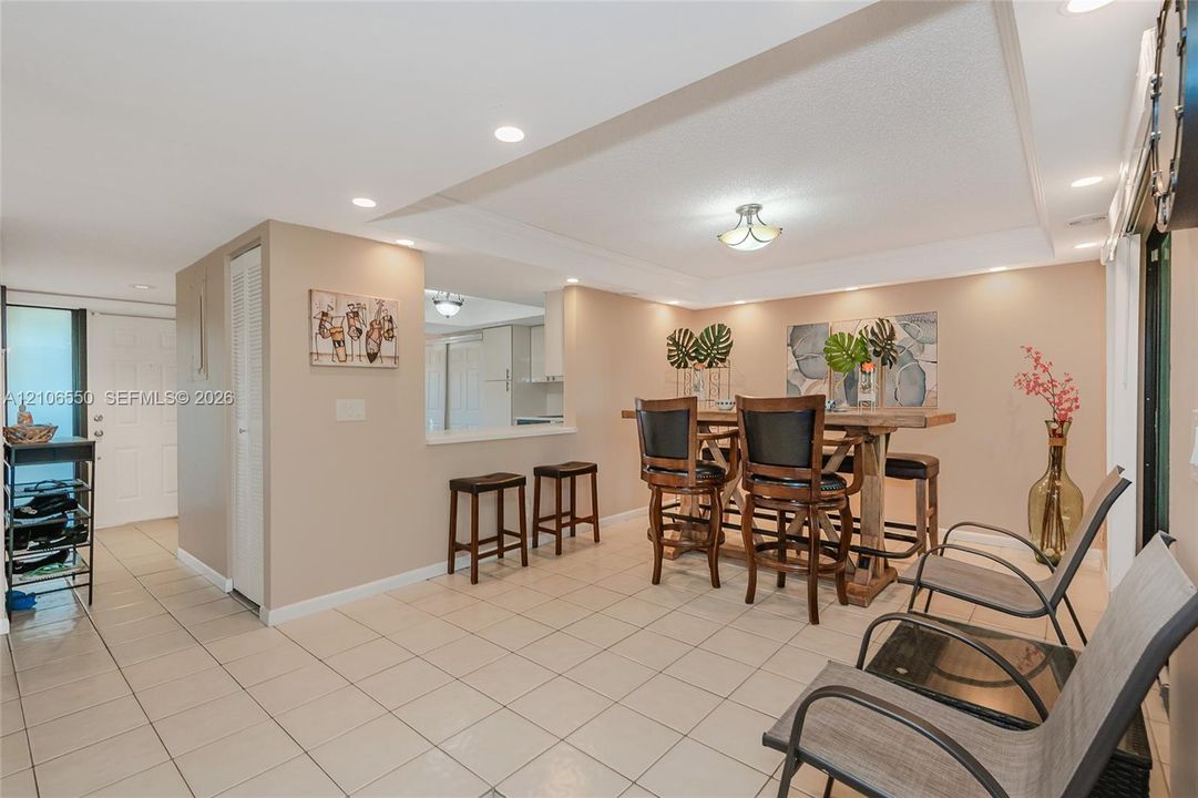Open-concept area featuring light-toned tile flooring, recessed ceiling lighting, and a pass-through opening
