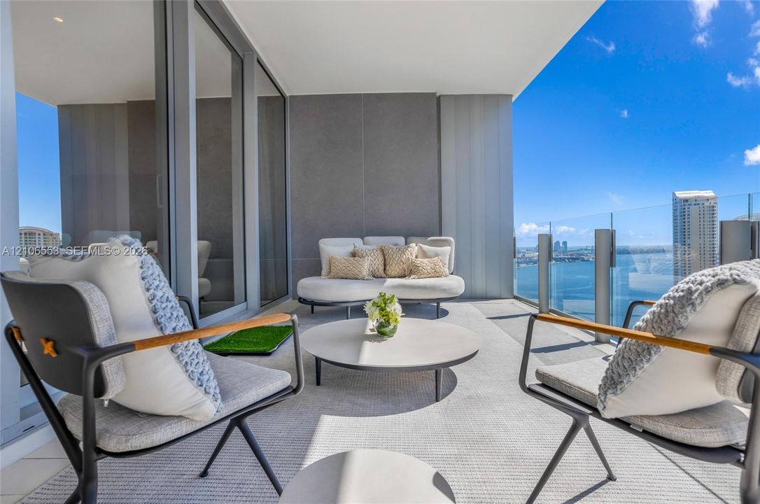Covered balcony featuring expansive glass-panel railings, large-format tile flooring, and floor-to-ceiling sliding glass doors