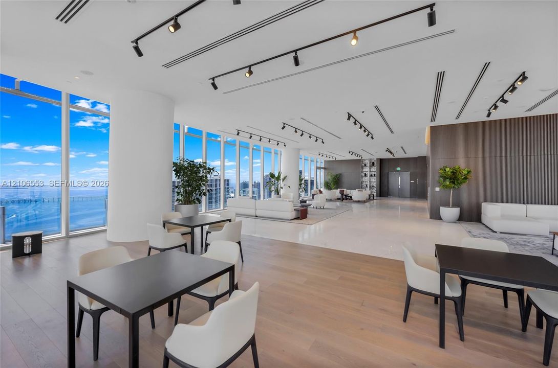 Open-concept space featuring floor-to-ceiling windows, wood-finish flooring, polished stone tile flooring, and integrated track lighting