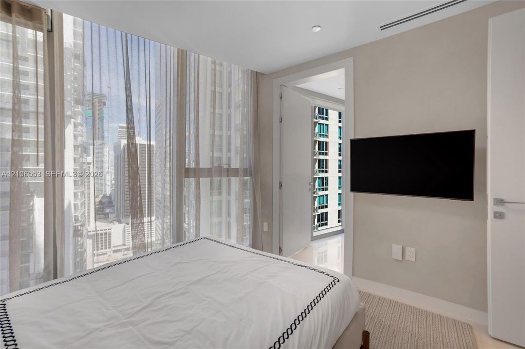 Floor-to-ceiling windows, polished stone flooring, recessed ceiling lighting, and wall-mounted television hardware
