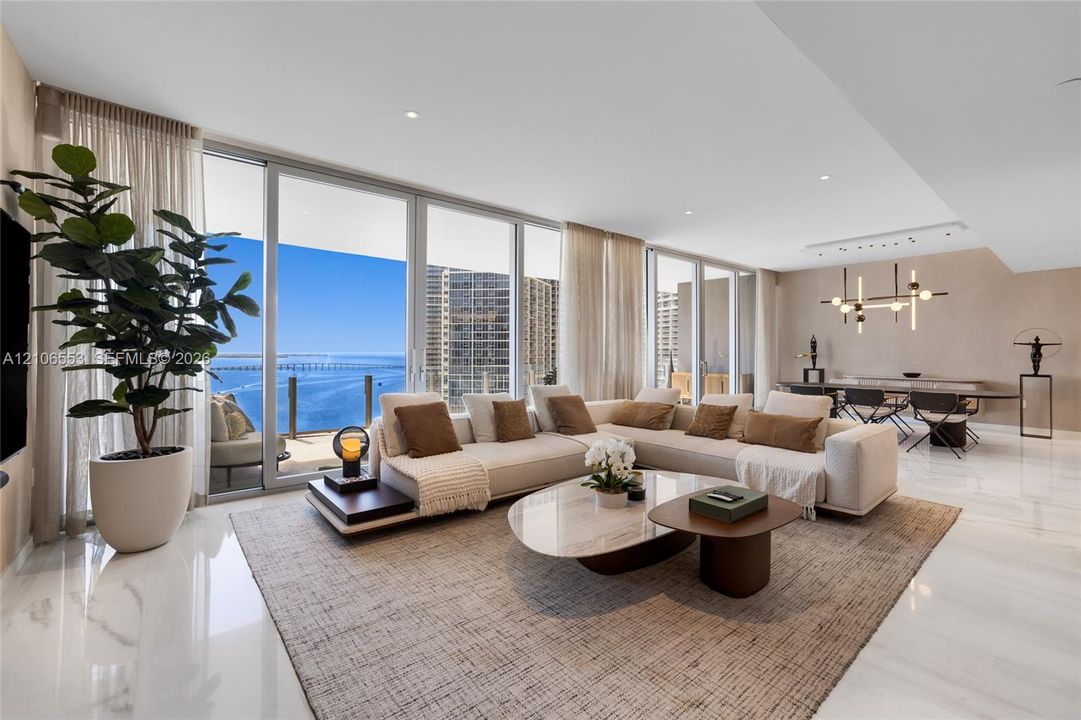 Open-concept living space featuring floor-to-ceiling glass sliding doors, polished stone-finish flooring, recessed lighting, and a modern tiered chandelier