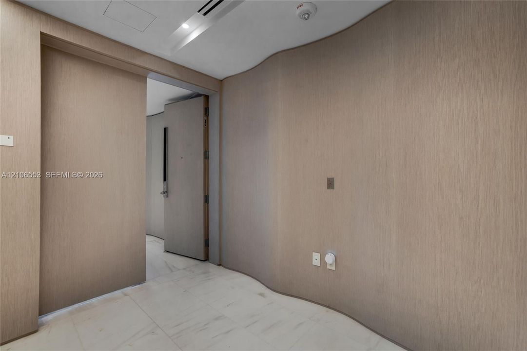 Curved wood-finish wall paneling, full-height sliding door, and stone-finish flooring