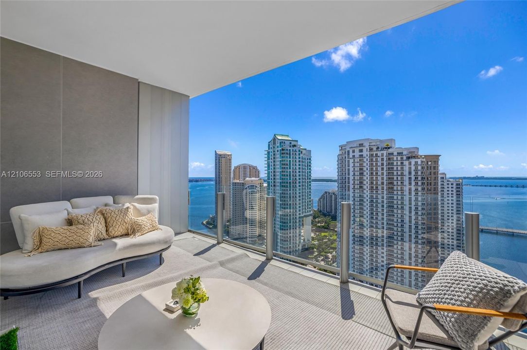Covered balcony featuring glass railing and large-format tile flooring