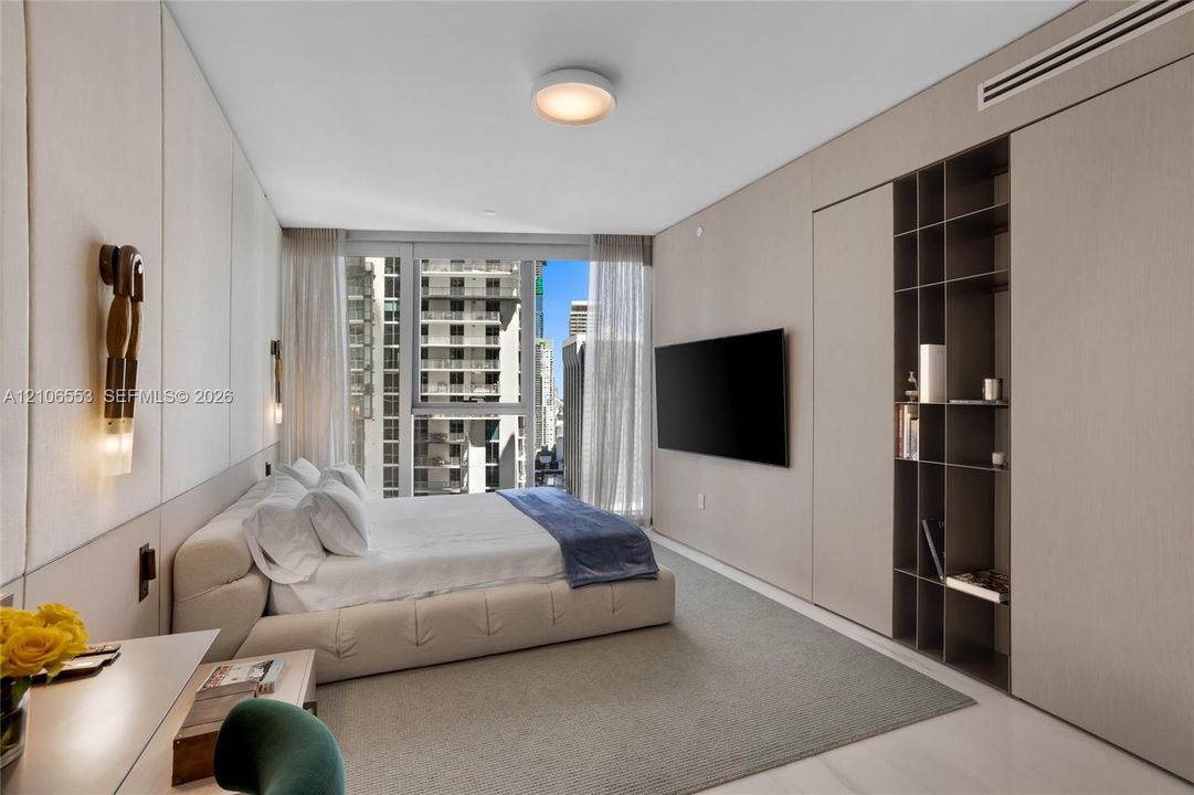 Wall-to-wall integrated cabinetry with open shelving, floor-to-ceiling windows, neutral upholstered wall paneling, and dual contemporary wall-mounted light fixtures