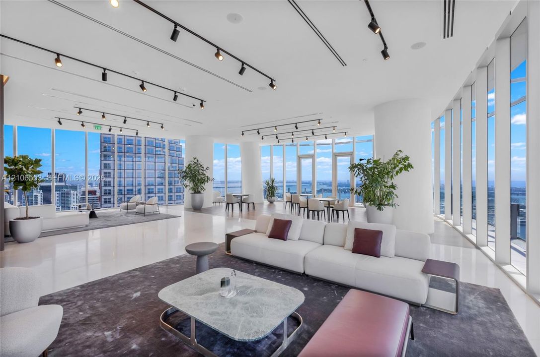 Expansive interior space featuring floor-to-ceiling windows, polished stone flooring, and adjustable overhead track lighting