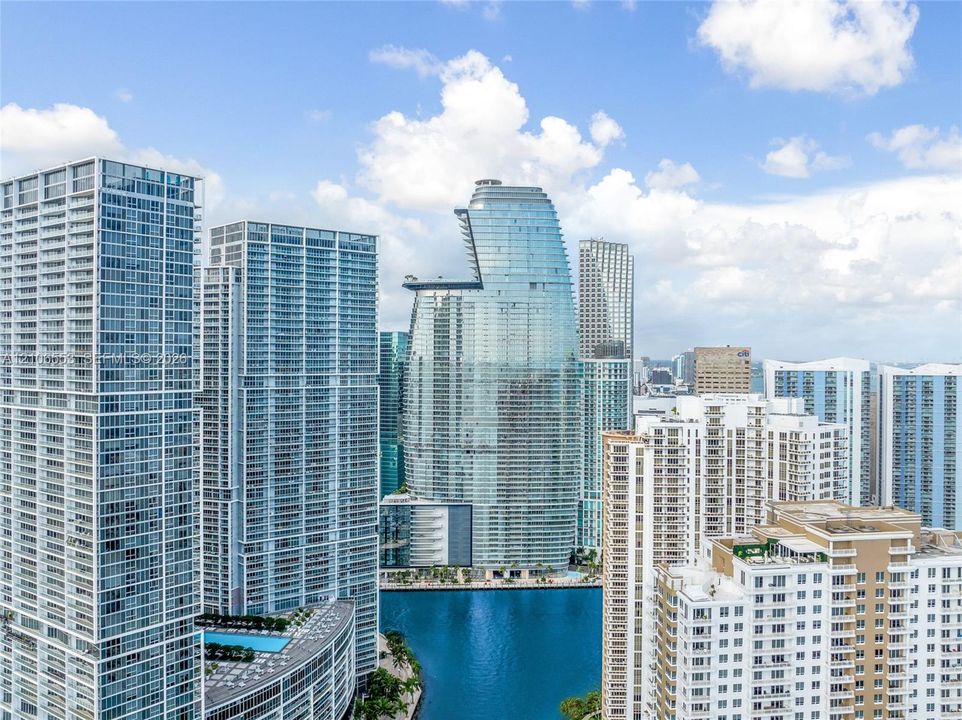 High-rise urban landscape featuring glass-clad skyscrapers, balcony-lined exterior facades, and water frontage
