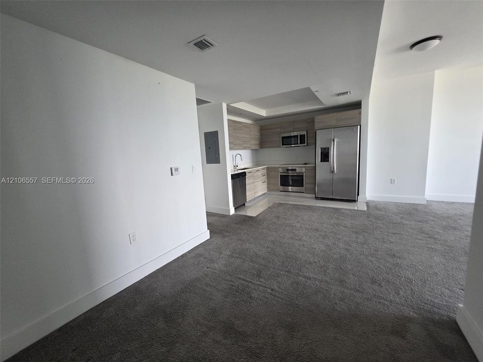 Kitchen featuring horizontal wood-finish cabinetry, stainless steel appliances, recessed lighting, and carpeted flooring