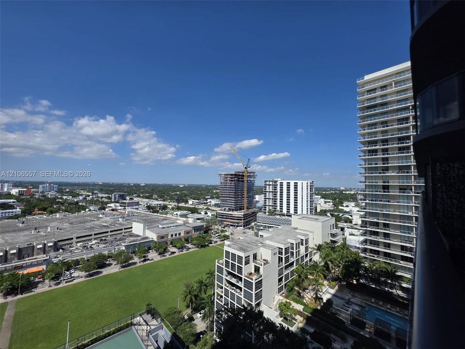 Elevated balcony featuring a glass panel railing and panoramic urban scenery