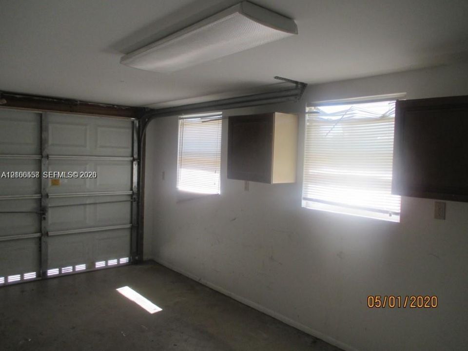 Enclosed garage featuring a metal sectional door, ceiling-mounted light fixture, and wall-mounted cabinetry