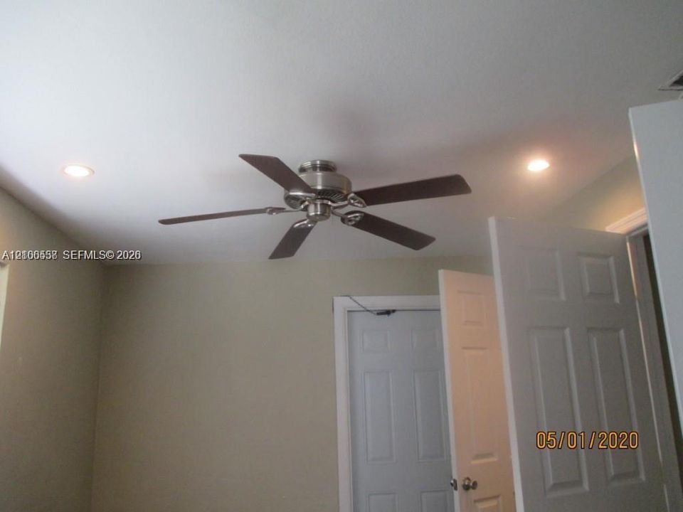 Five-blade metal ceiling fan with dark finish paddles, recessed lighting, and six-panel interior doors