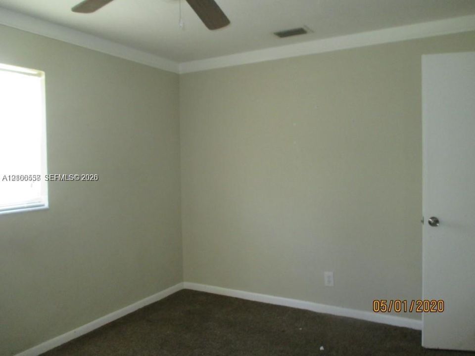 Neutral wall tones, carpeted flooring, and a ceiling fan with integrated lighting