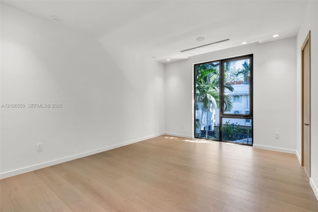 Interior space featuring wood-finish flooring, recessed lighting, floor-to-ceiling dark-framed windows, and minimalist flush-mount doors