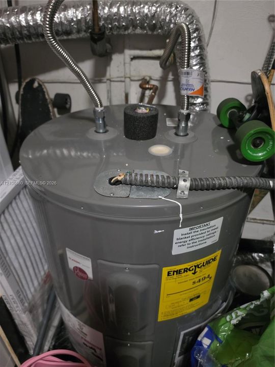 Electric water heater featuring braided metal supply lines, a protective insulation cap, and a metal-clad electrical conduit