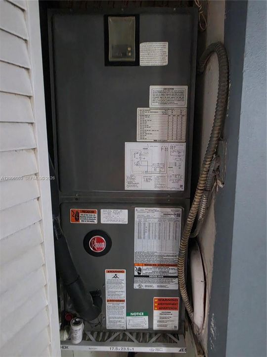 Rheem HVAC system featuring an integrated metallic cabinet, diagnostic information placards, and accessible air filtration housing