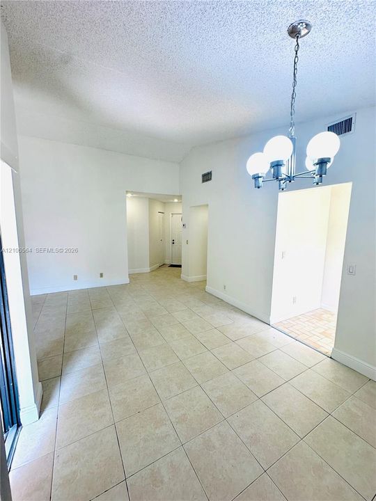 Vaulted ceilings, large-format tile flooring, and a multi-globe chandelier featuring a polished metallic finish
