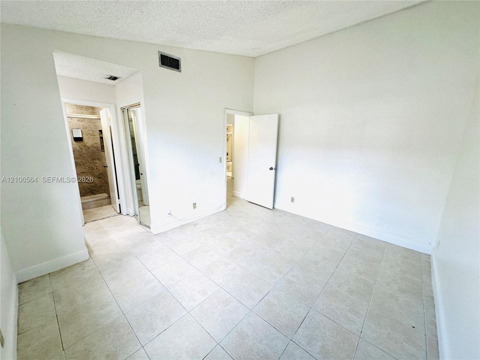 Room featuring vaulted ceilings, light-toned ceramic tile flooring, and a mirrored closet door