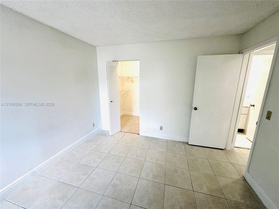 Neutral-toned tile flooring, solid-core interior doors, and built-in closet storage