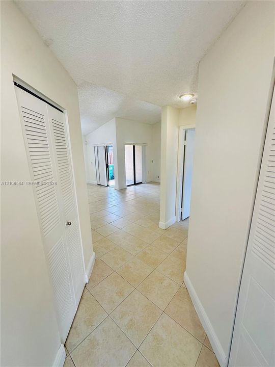 Interior hallway featuring square tile flooring, dual louvered closet doors, and sliding glass doors