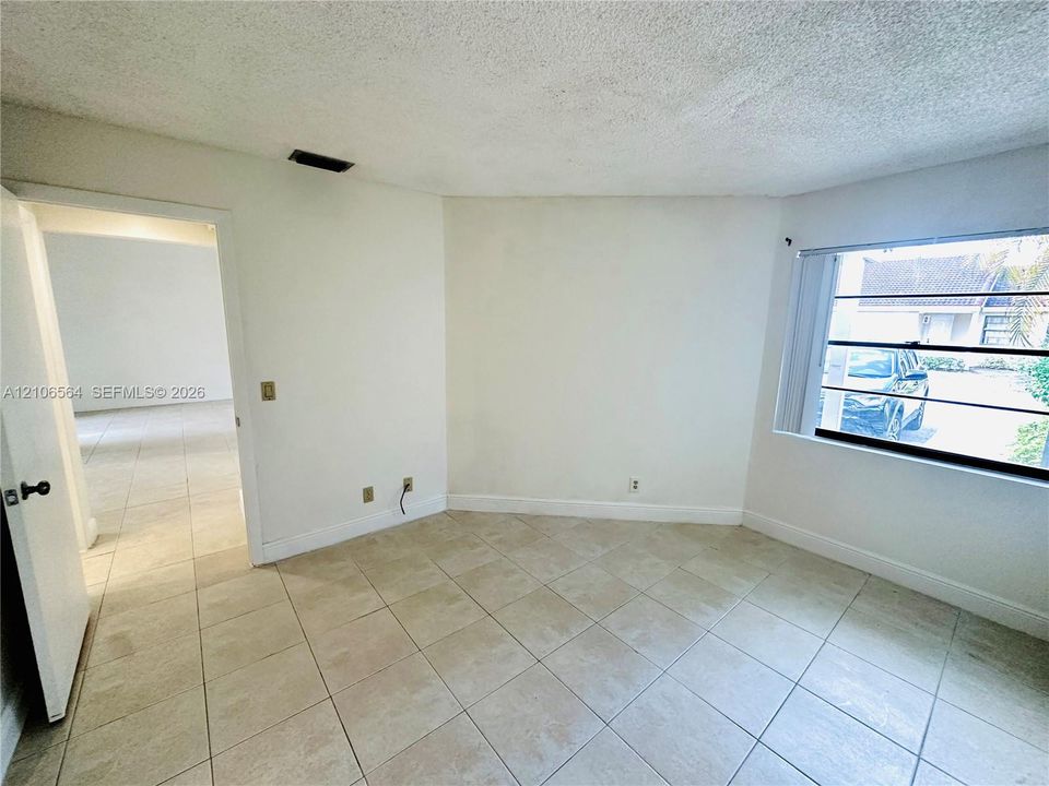 Interior space featuring neutral tile flooring, textured ceiling, and a multi-pane horizontal window