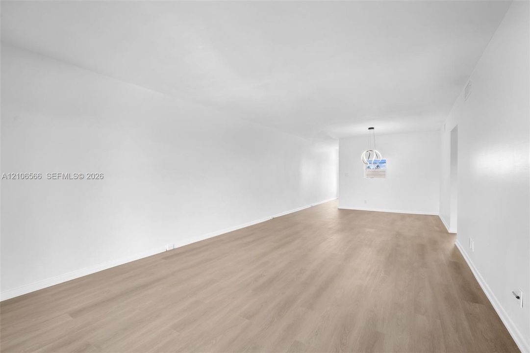Neutral interior featuring wood-finish flooring, crisp white walls, and a contemporary circular pendant light fixture