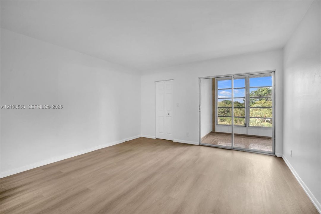 Neutral-toned wood-finish flooring, sliding glass doors, and a paneled interior door