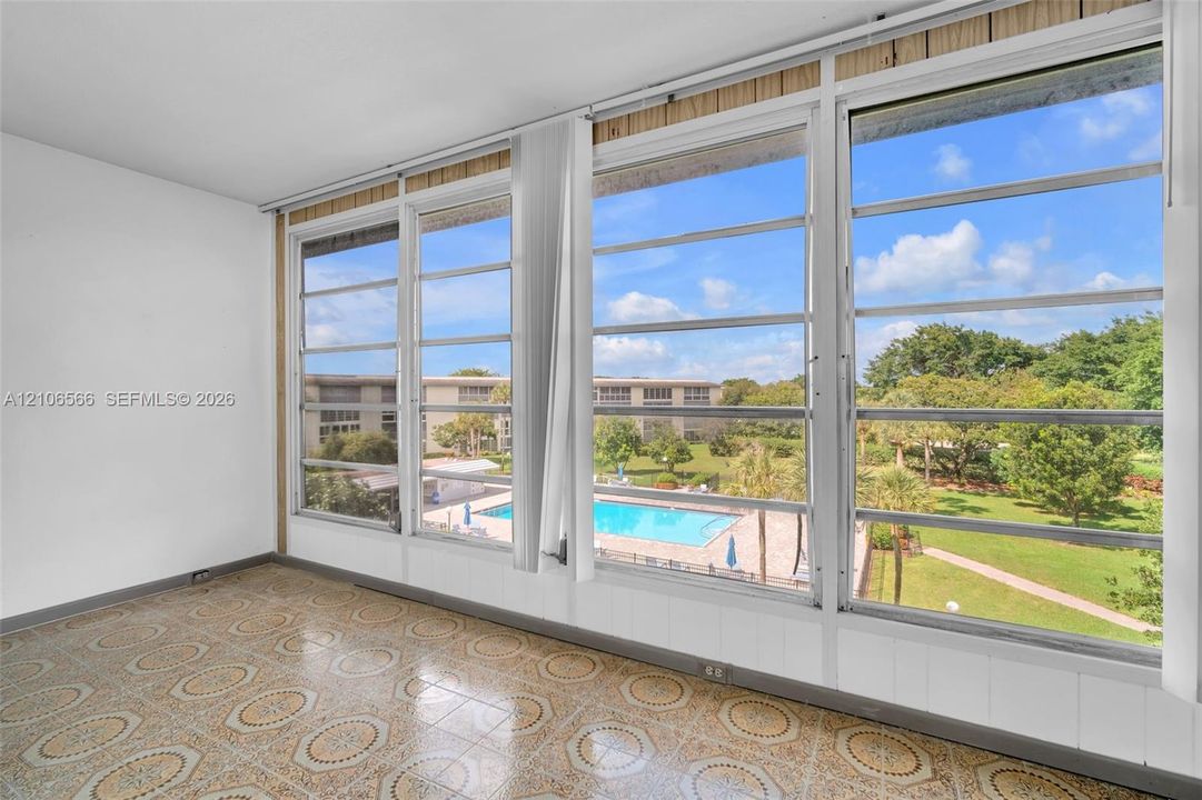 Expansive windows with metal frames, patterned tile flooring, and white paneled walls