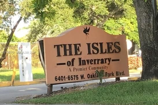 Freestanding monument sign featuring decorative raised lettering and an arched silhouette, situated within landscaped grounds