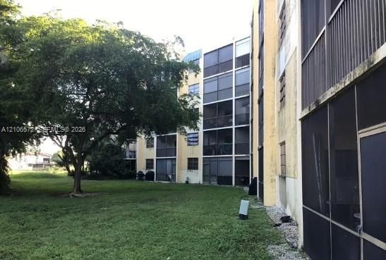 Multi-story exterior featuring screened balconies and mature landscaping