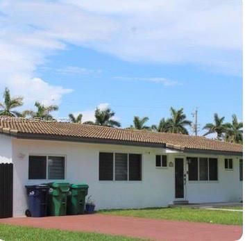 Exterior facade featuring a white stucco finish, a low-pitched tiled roof, and a paved driveway