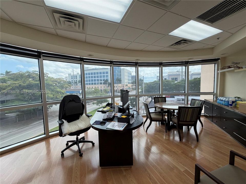 Curved wall of floor-to-ceiling windows with panoramic exterior exposure, wood-finish flooring, and built-in dark cabinetry