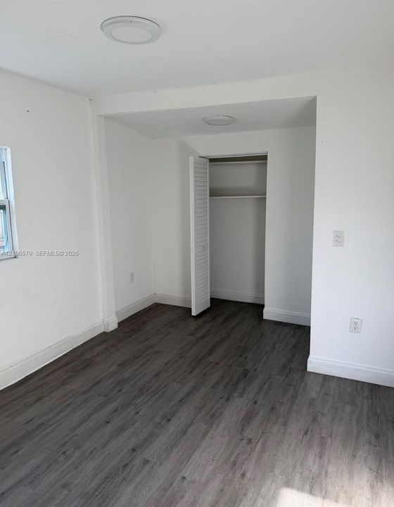 Room featuring wood-finish flooring, recessed ceiling lighting, and a closet with louvered doors
