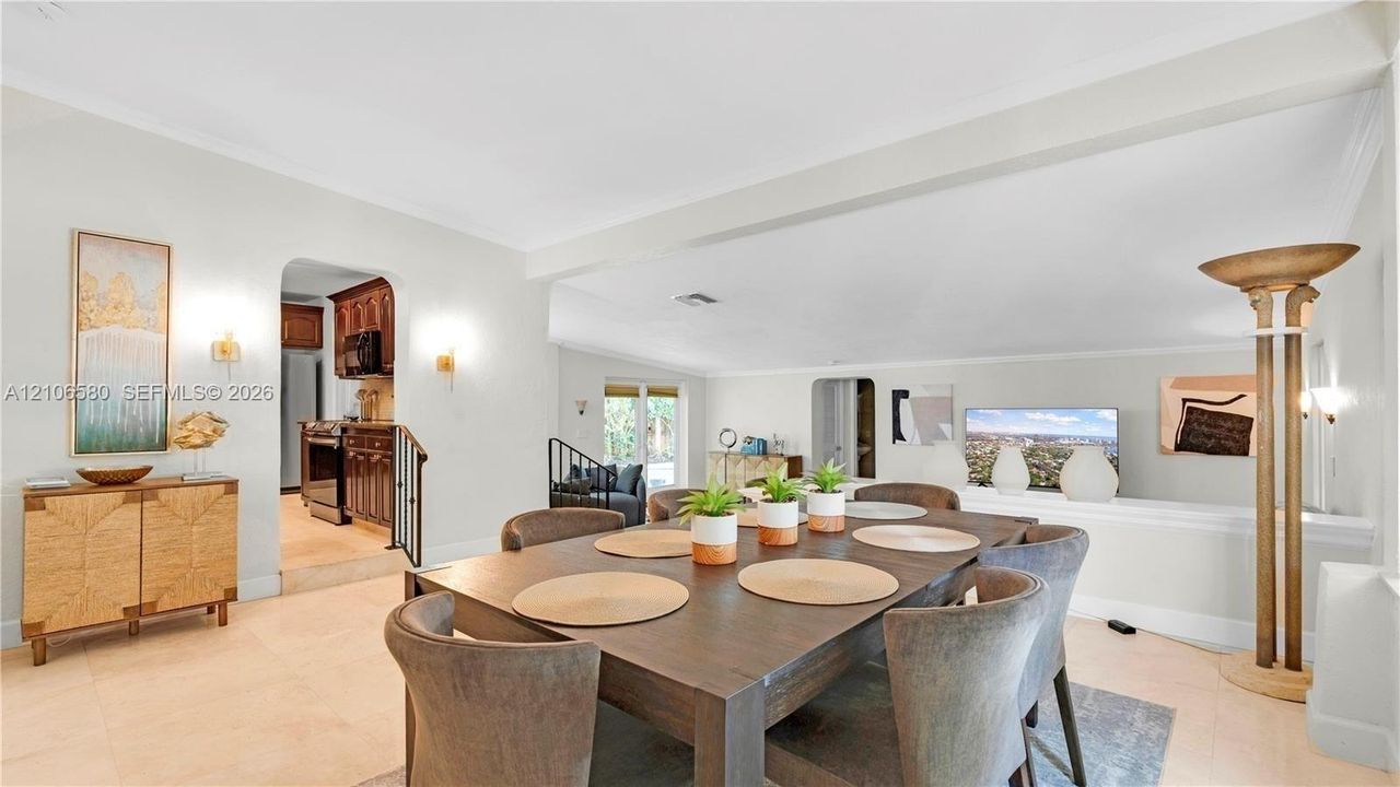 Open-concept interior featuring neutral tile flooring, recessed lighting, crown molding, arched entryways, and wall-mounted sconce lighting