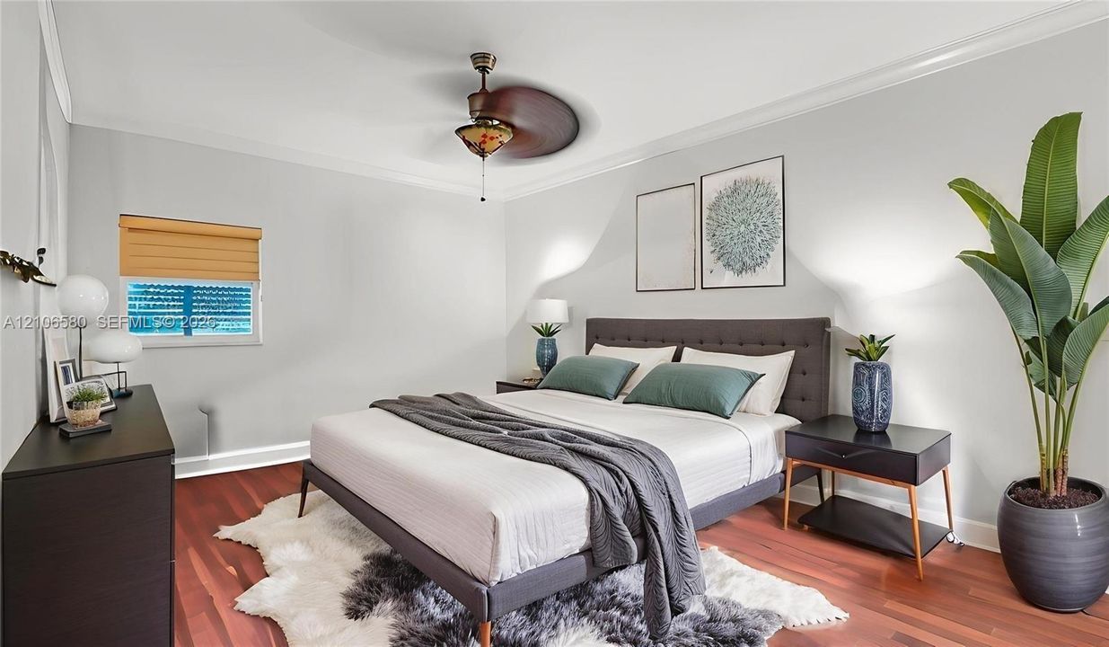 Room featuring wood-finish flooring, crown molding, and a decorative ceiling fan with integrated light fixture