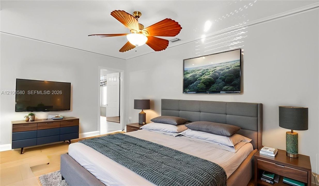 Spacious room featuring wood-finish flooring and a central ceiling fan with leaf-shaped blades