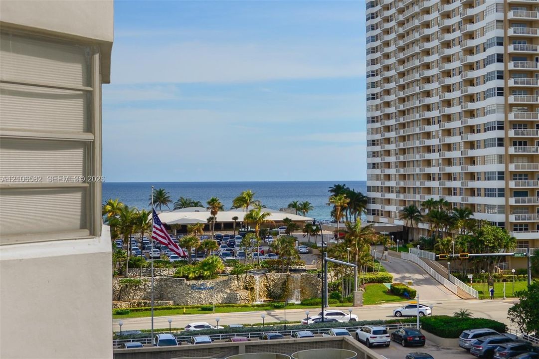 Exterior balcony featuring a direct horizon line of the ocean, stone-faced retaining walls, and mature palm trees
