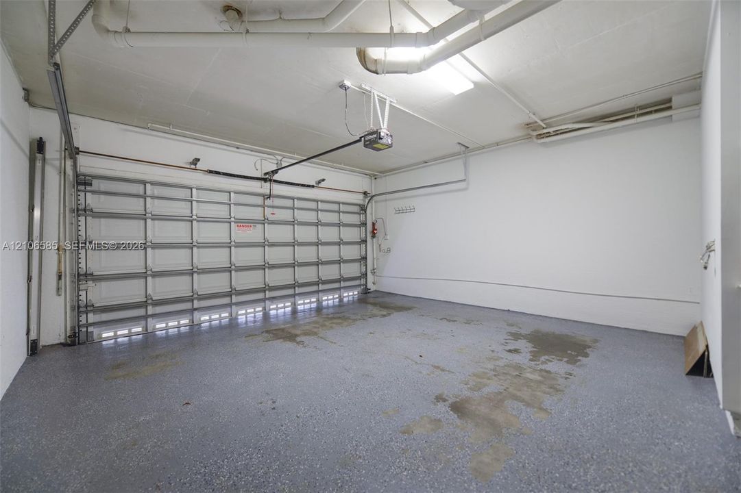 Multi-car garage featuring a sectional overhead door, epoxy-coated flooring, and overhead lighting