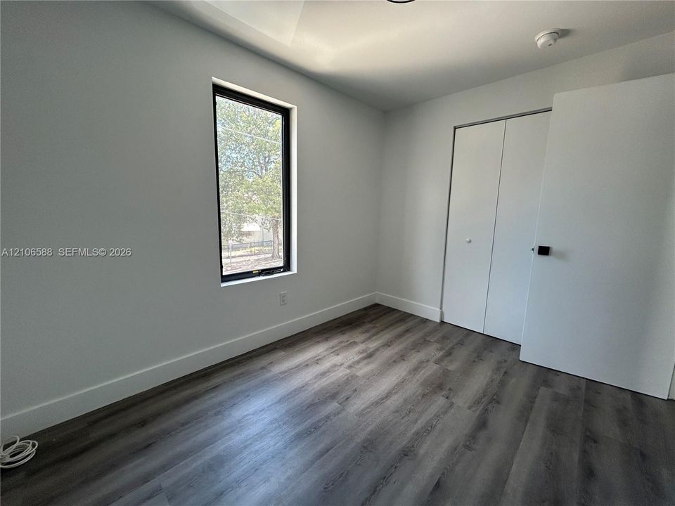 Wood-finish flooring, neutral wall tones, bi-fold closet doors, and a casement window with a black frame