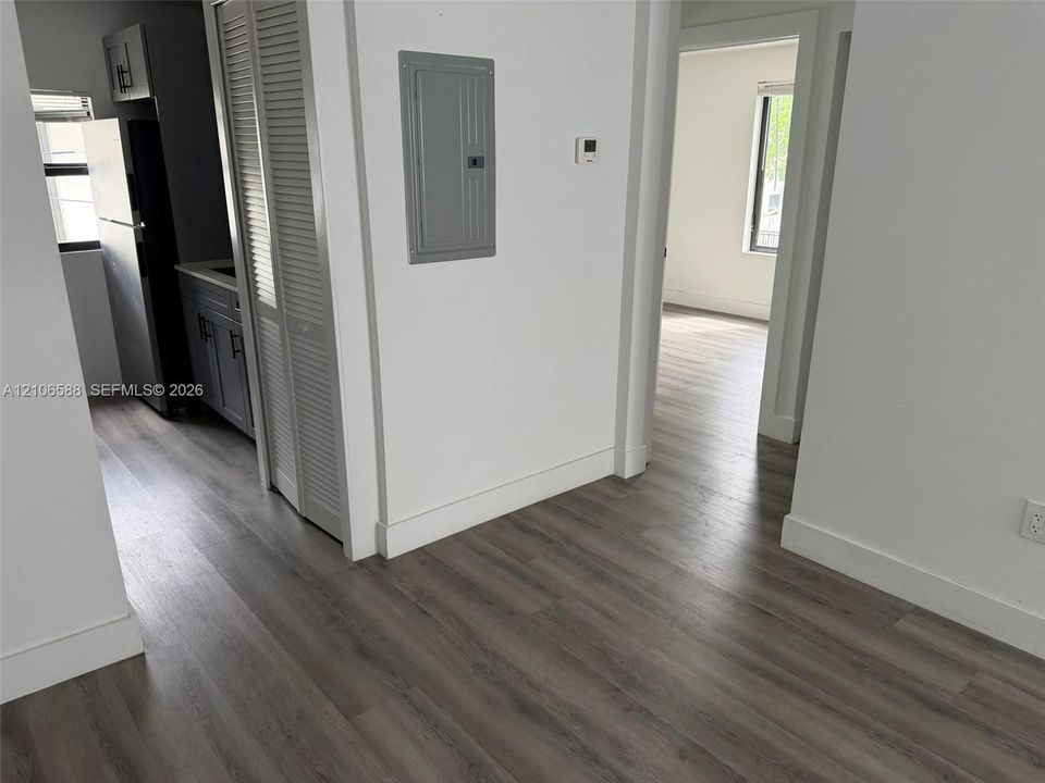 Wood-finish flooring, white walls, louvered closet doors, and neutral grey cabinetry