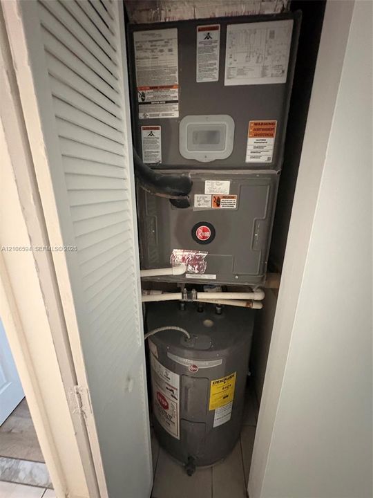 Utility closet featuring a Rheem HVAC air handler and a vertical tank-style water heater
