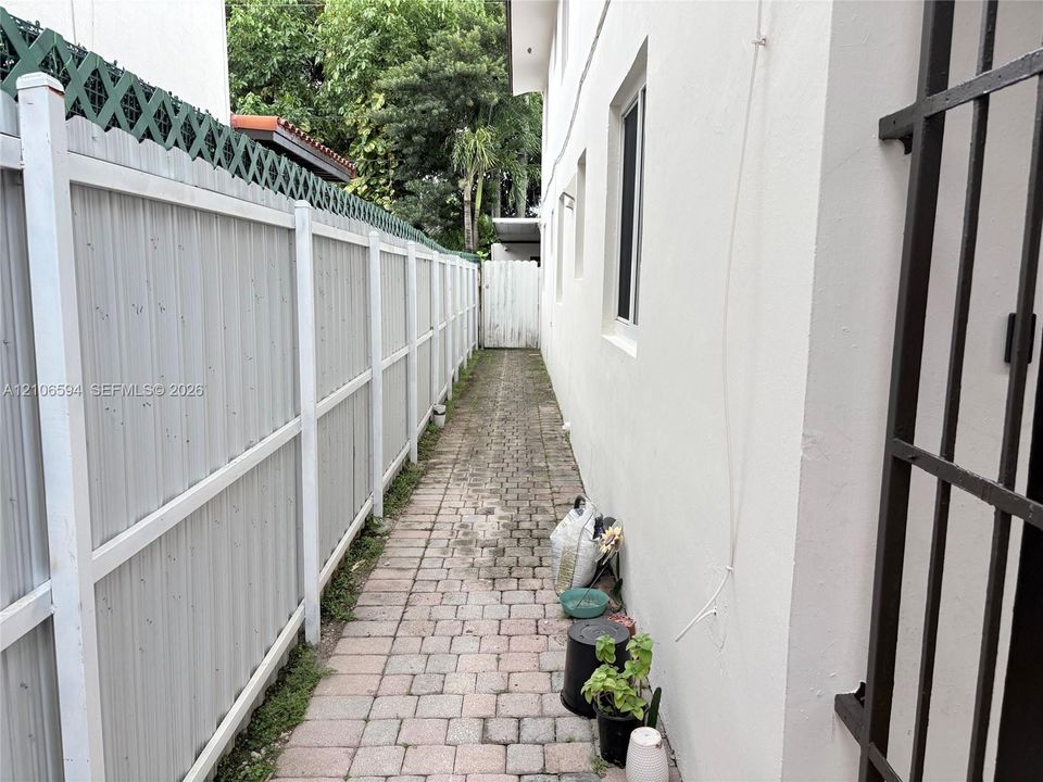 Side yard featuring a stone-paver walkway and vertical privacy fencing with lattice screening