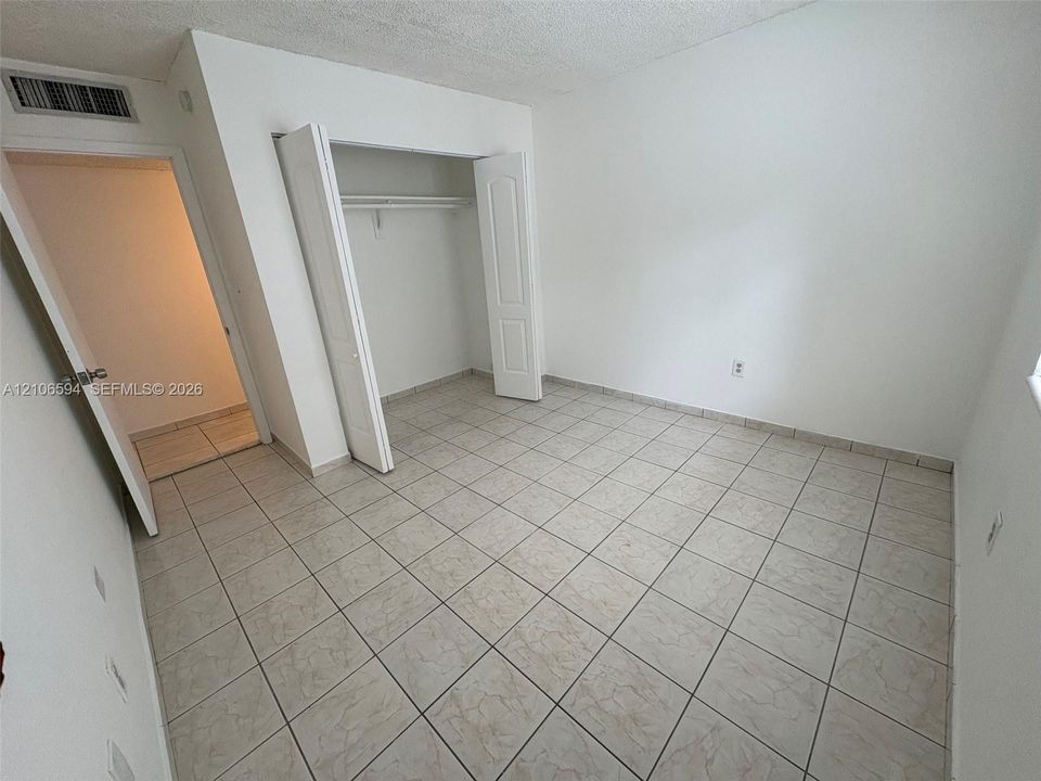 Room featuring neutral wall finishes, tile flooring, and a reach-in closet with double-panel doors