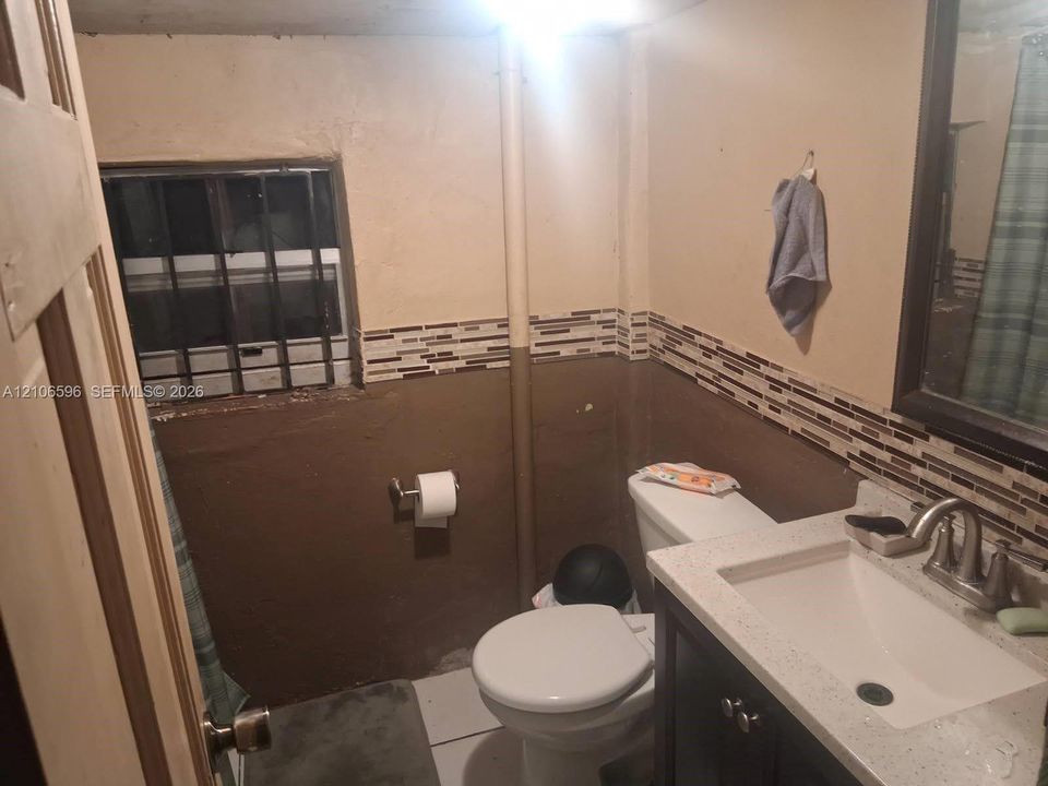 Bathroom featuring a vanity with a light-toned countertop, integrated basin, and metal faucet, complemented by decorative horizontal tile accents and a framed mirror