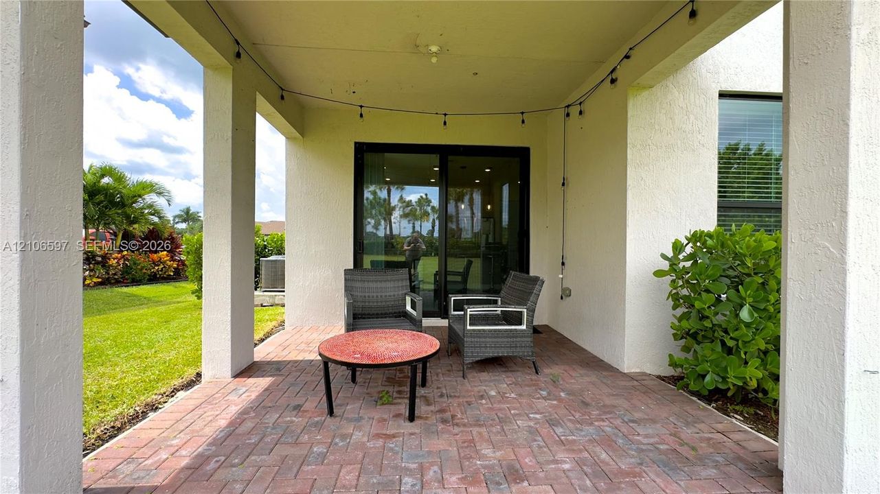 Covered patio featuring brick pavers, support columns, and sliding glass door access