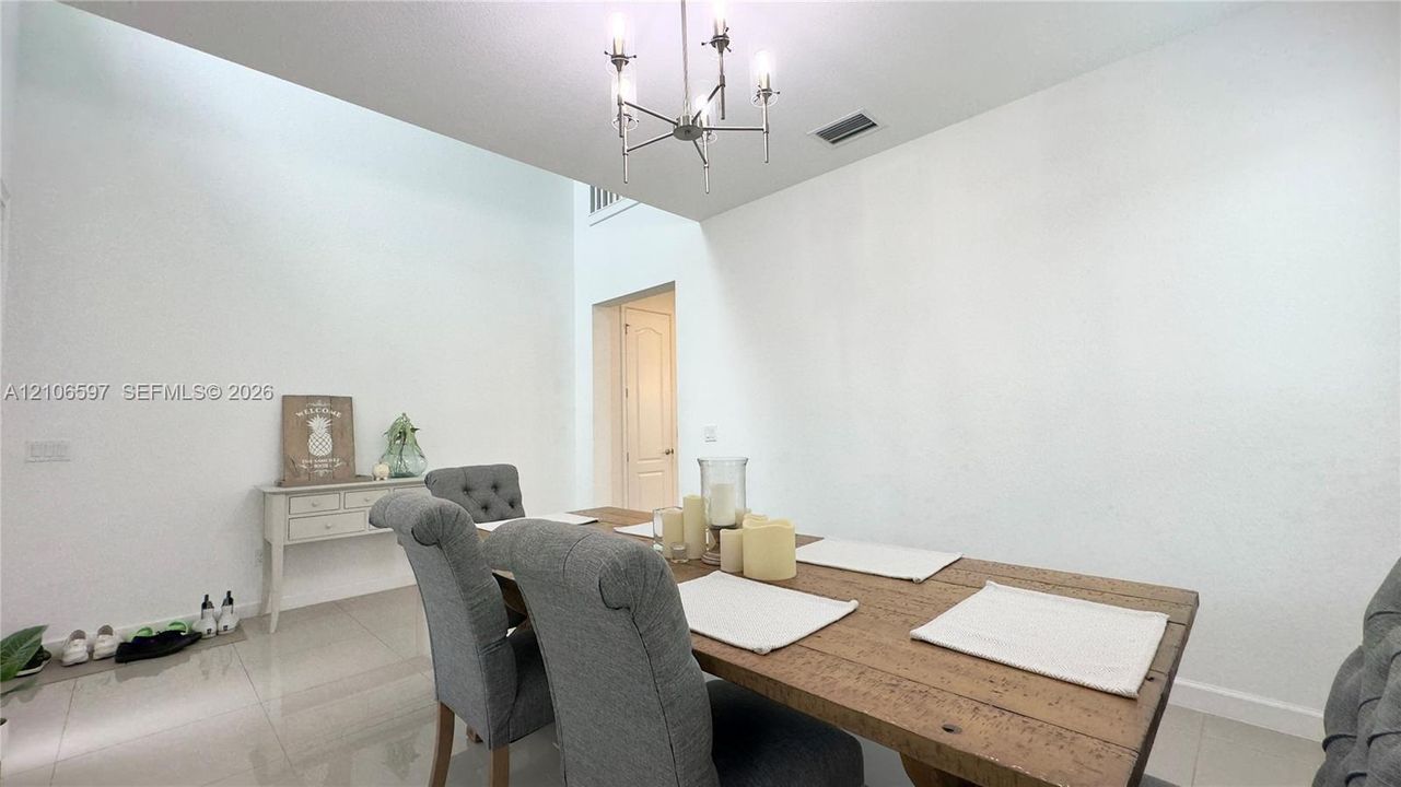 Vaulted ceilings featuring a multi-arm metallic chandelier, neutral wall finish, and polished stone-finish flooring
