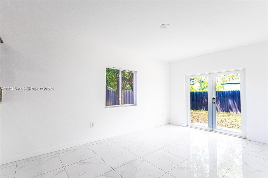 Polished stone-look flooring, dual-pane window, and glass-paned French doors opening to an exterior area