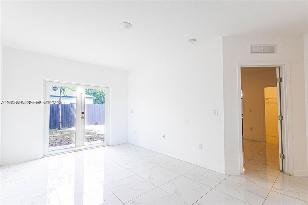 Interior space featuring large-format light-toned tile flooring, recessed lighting, and double-panel glass doors providing access to the exterior