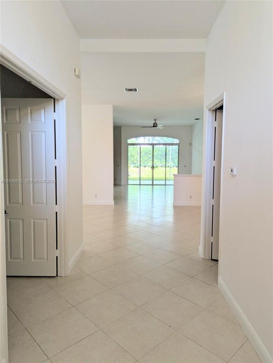 Interior hallway with tile flooring, arched window, and sliding glass doors